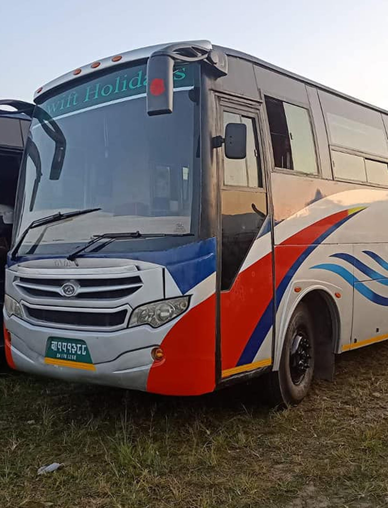 The girls enter the doors of a blue bus that has arrived at the bus stop.